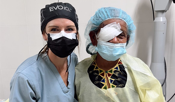 Optometrist examining a patient's eye with a handheld device.